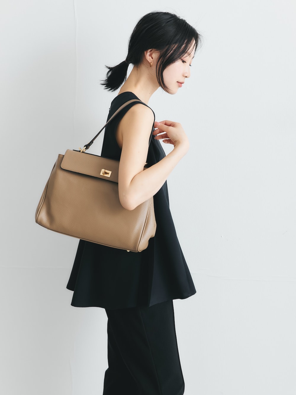 ブルー系のシャツ/ブラウス、ベージュ系のハンドバッグを着用したレディースの夏コーディネートの3枚目の写真