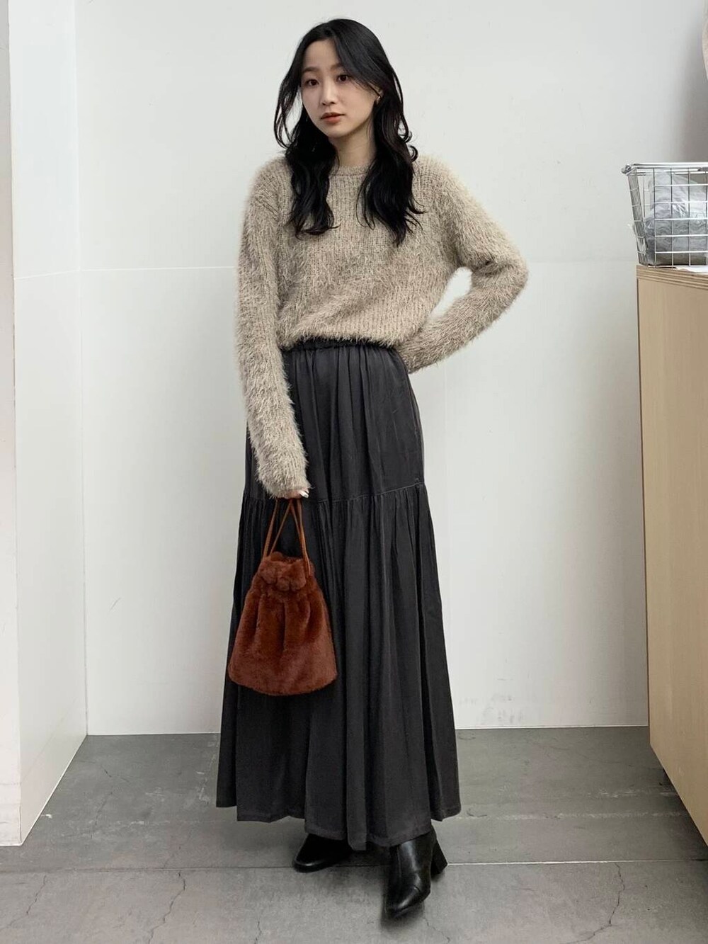 ブラック系のブーツ、ブラウン系のショルダーバッグ、グレー系のスカートを着用したレディースの冬コーディネートの3枚目の写真