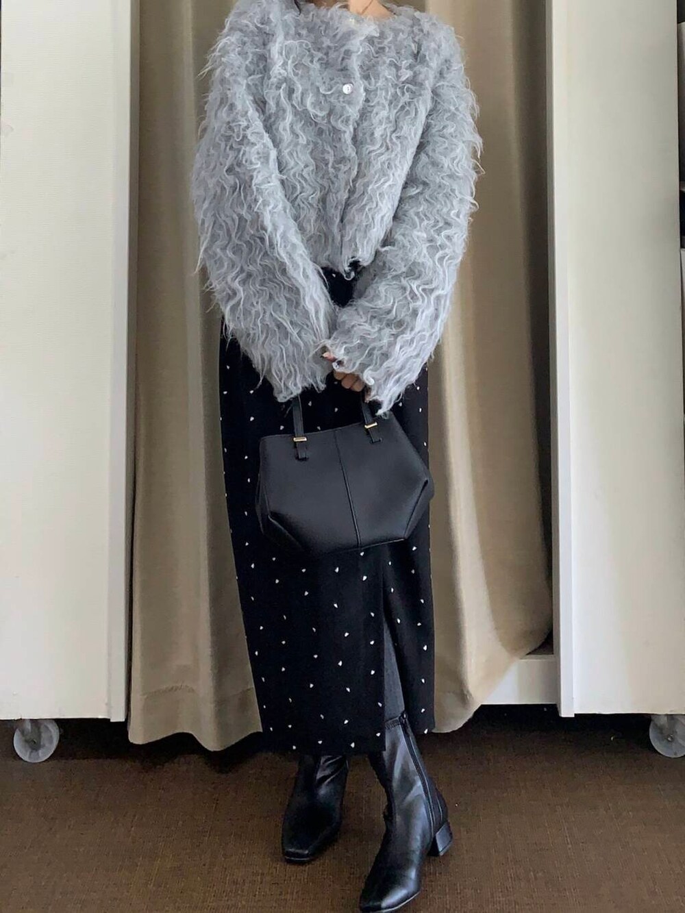 ブラック系のブーツ、ブラック系のショルダーバッグ、ブラック系のスカートを着用したレディースの秋コーディネートの2枚目の写真