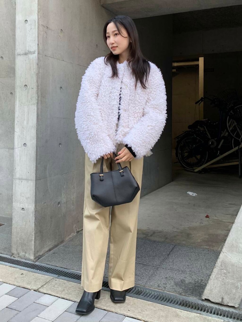 ブラック系のショルダーバッグ、ブラック系のブーツ、ベージュ系のチノパンツを着用したレディースの冬コーディネートの5枚目の写真