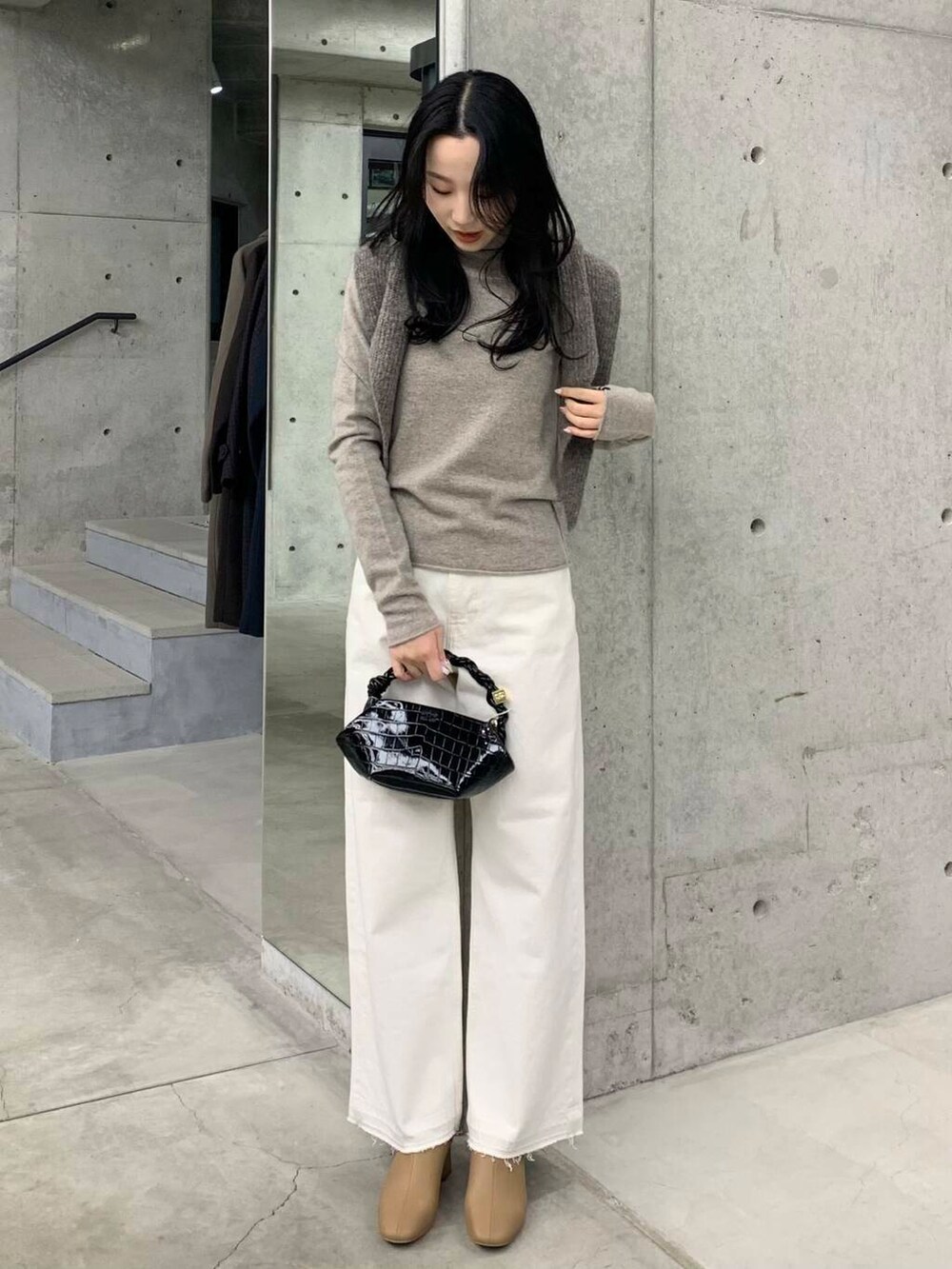 ホワイト系のデニムパンツ、ベージュ系のブーツ、ブラック系のショルダーバッグを着用したレディースの冬コーディネートの2枚目の写真