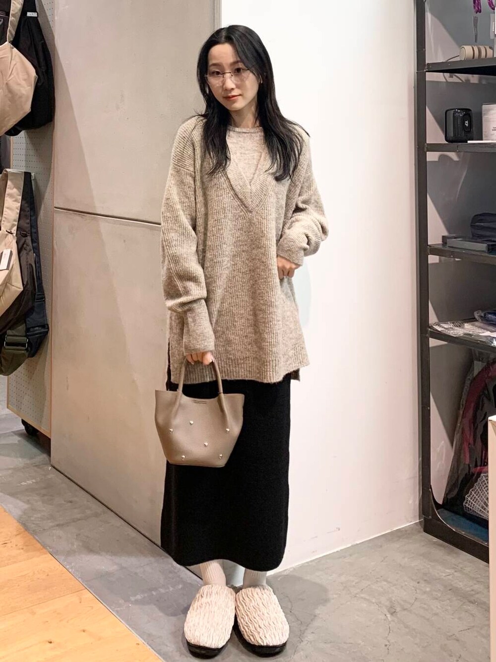 グレー系のショルダーバッグ、ベージュ系のニット/セーター、ブラック系のスカートを着用したレディースの冬コーディネートの2枚目の写真
