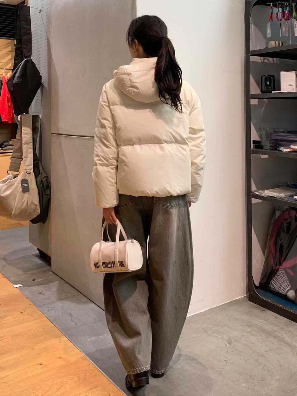 ブラック系のブーツ、ホワイト系のボストンバッグ、グリーン系のデニムパンツを着用したレディースの冬コーディネートの5枚目の写真