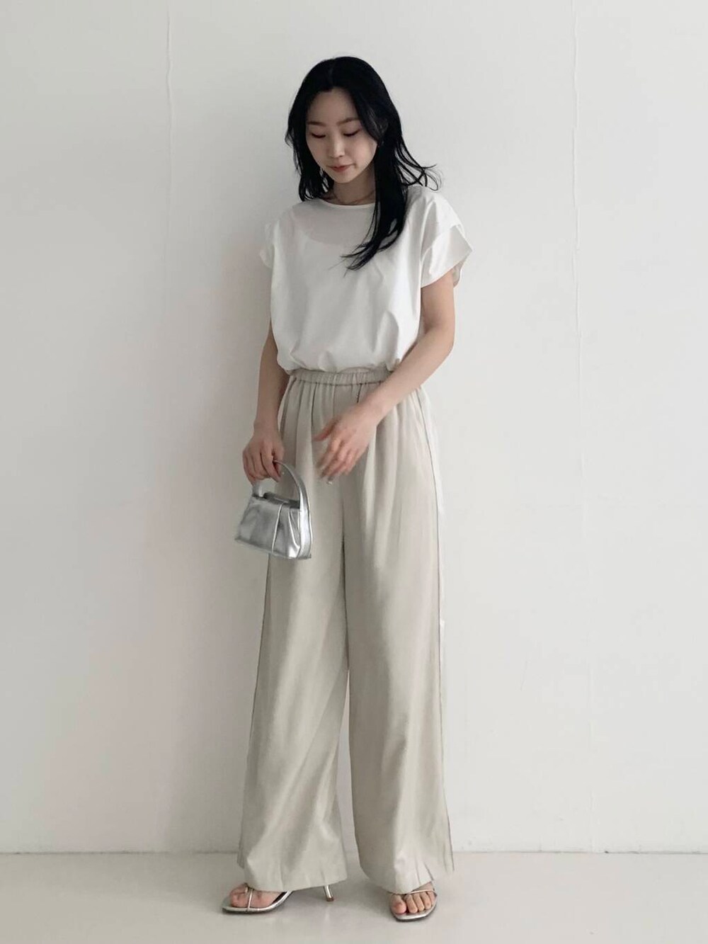 ベージュ系のその他パンツ、シルバー系のハンドバッグ、ホワイト系のTシャツ/カットソーを着用したレディースの春コーディネートの2枚目の写真