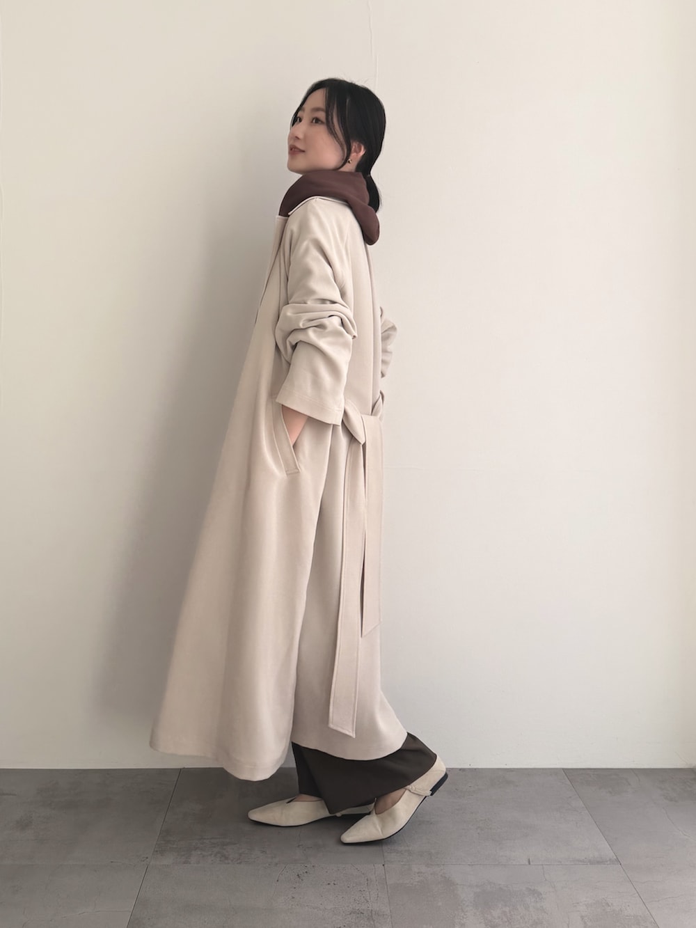 ベージュ系のトレンチコート、ブラウン系のパーカー、ブラウン系のその他パンツを着用したレディースの春コーディネートの3枚目の写真