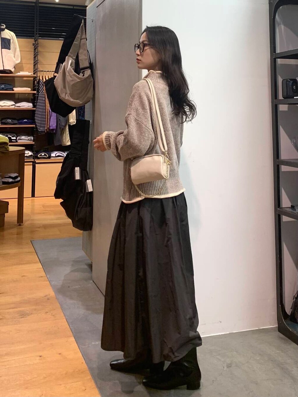 グレー系のスカート、ベージュ系のニット/セーター、ブラック系のブーツを着用したレディースの冬コーディネートの5枚目の写真