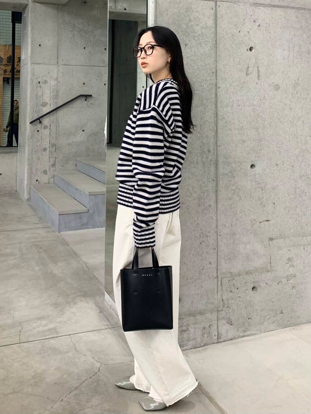 ホワイト系のデニムパンツ、ブラック系のハンドバッグ、グレー系のパンプスを着用したレディースの冬コーディネートの6枚目の写真