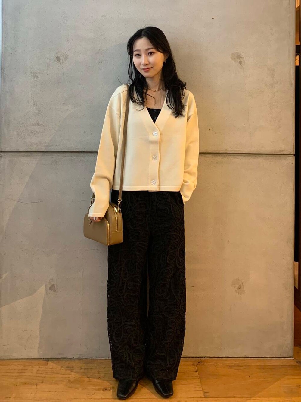 ベージュ系のショルダーバッグ、ホワイト系のカーディガン/ボレロ、ブラック系のブーツを着用したレディースの秋コーディネートの4枚目の写真