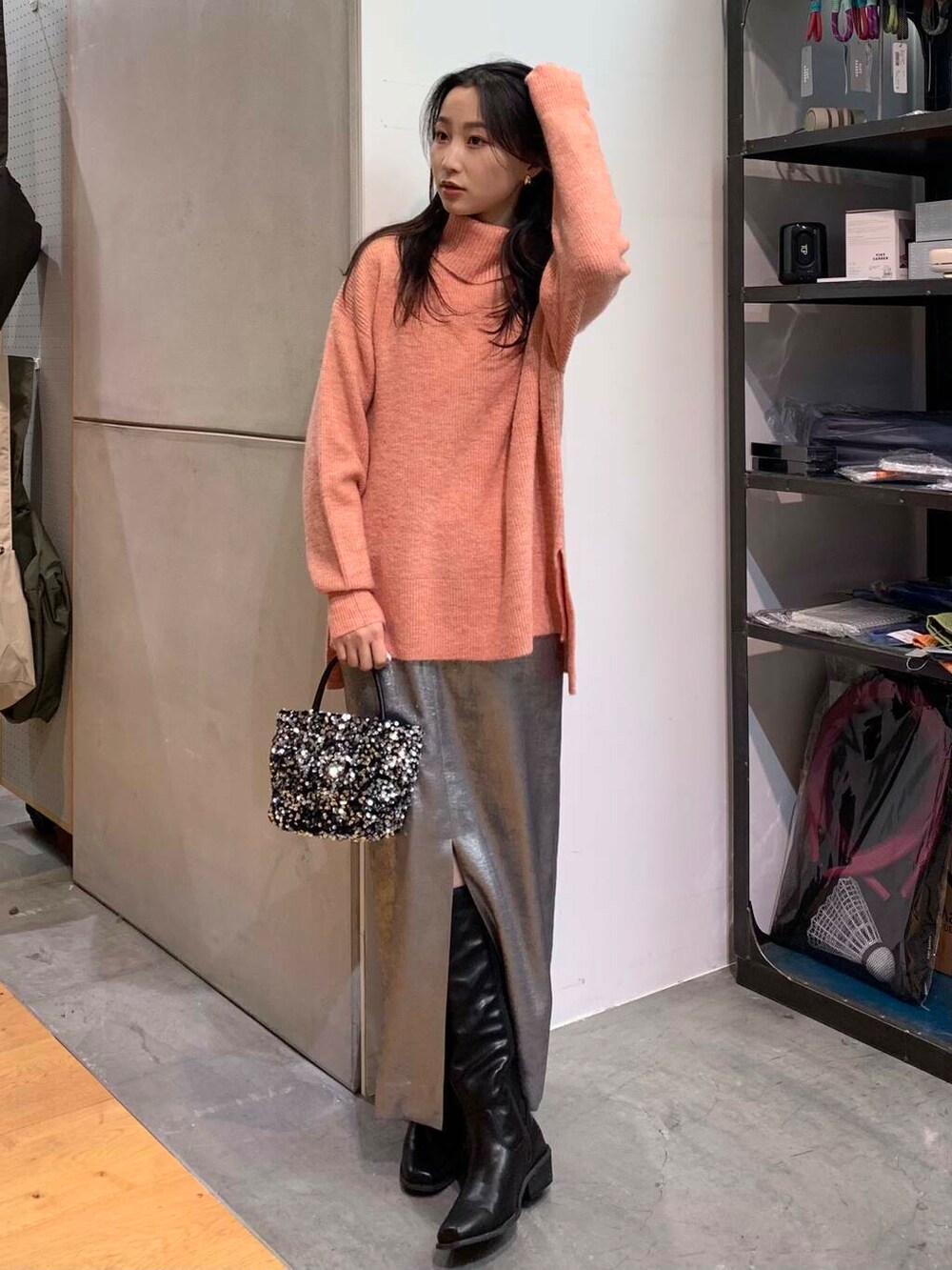 シルバー系のショルダーバッグ、ブラック系のブーツ、シルバー系のスカートを着用したレディースの冬コーディネートの2枚目の写真