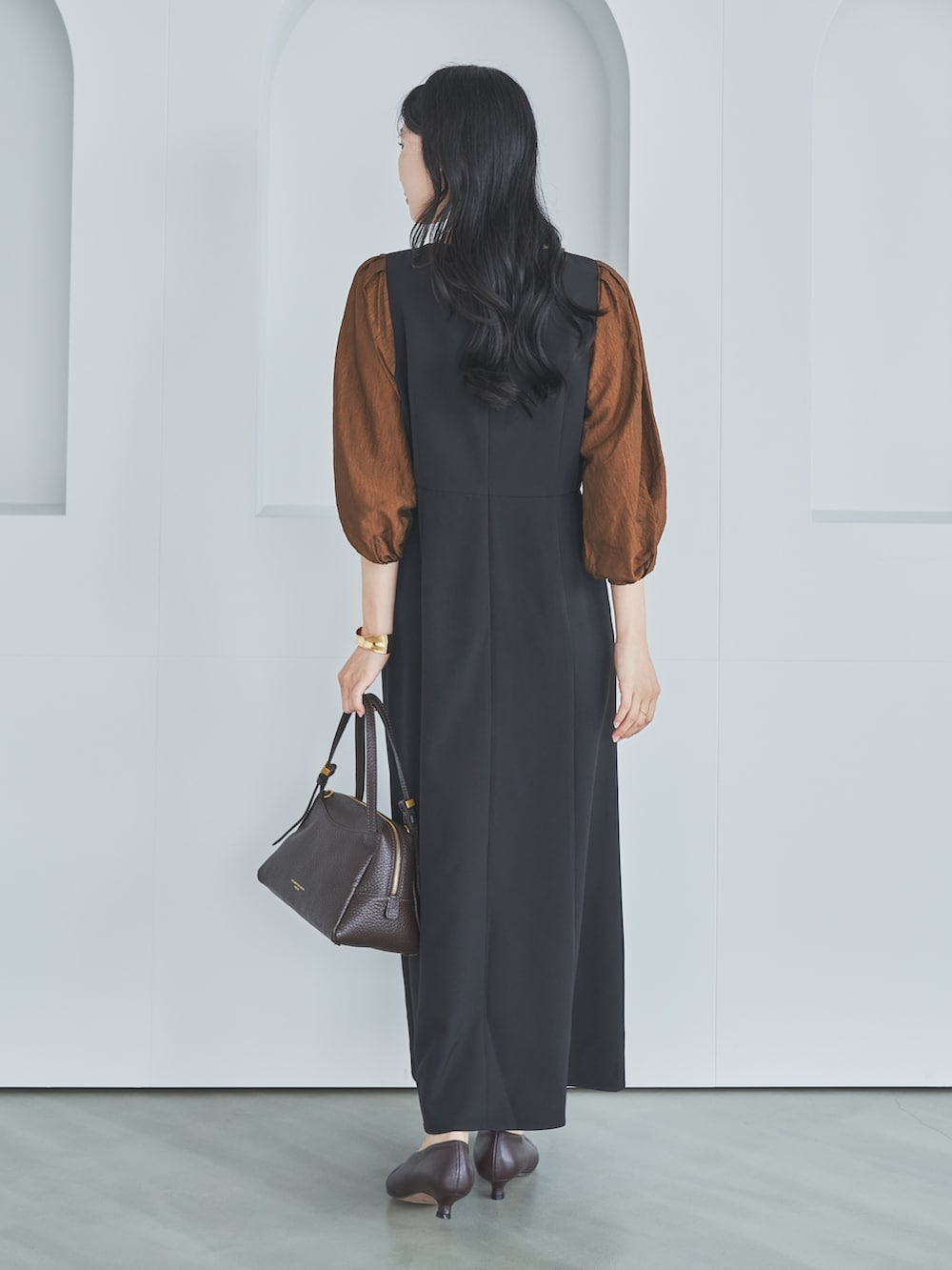 ブラック系のワンピース、ブラウン系のショルダーバッグ、ブラウン系のパンプスを着用したレディースの秋コーディネートの3枚目の写真