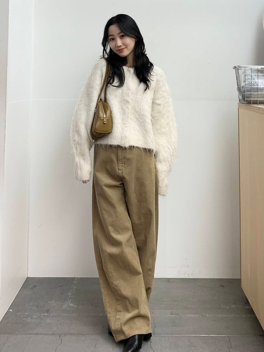 ブラック系のブーツ、グリーン系のボストンバッグ、ベージュ系のその他パンツを着用したレディースの冬コーディネートの2枚目の写真