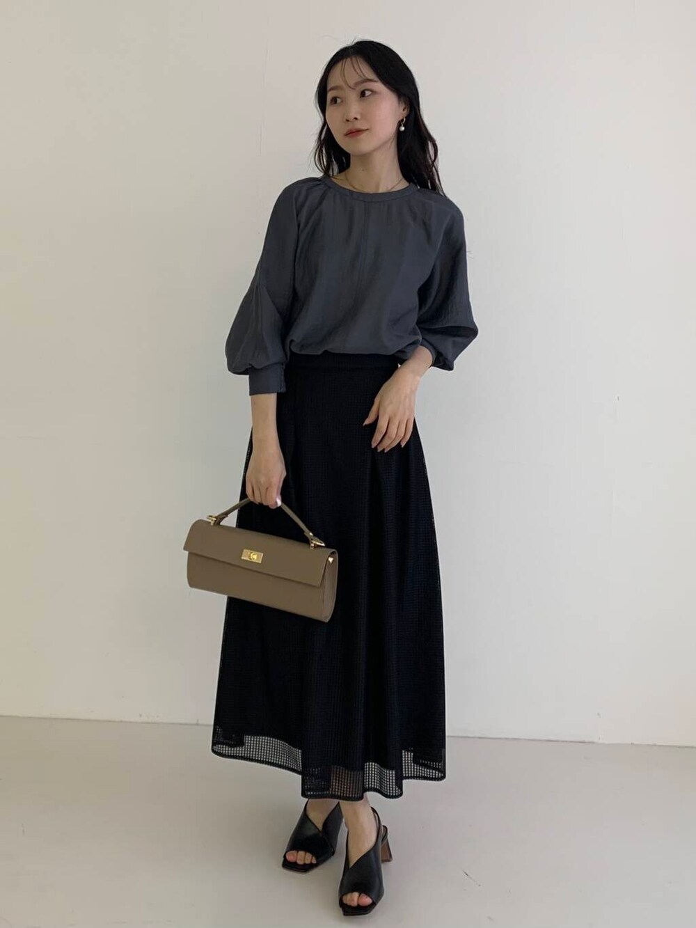 グレー系のシャツ/ブラウス、ブラック系のスカート、ベージュ系のショルダーバッグを着用したレディースの春コーディネートの2枚目の写真