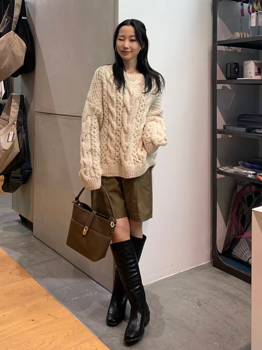 ホワイト系のニット/セーター、ベージュ系のハンドバッグ、ブラック系のブーツを着用したレディースの冬コーディネートの3枚目の写真