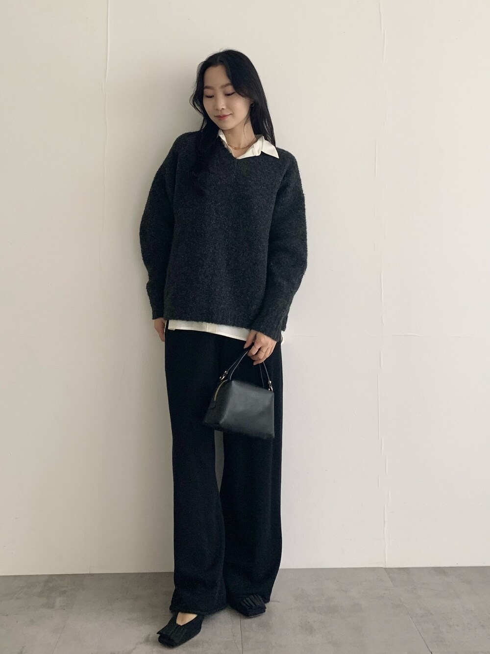 グレー系のニット/セーター、ホワイト系のシャツ/ブラウス、ブラック系のその他パンツを着用したレディースの秋コーディネートの2枚目の写真