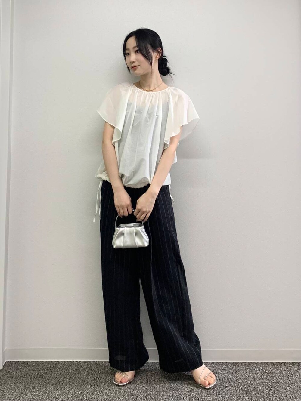 シルバー系のハンドバッグ、ブラック系のその他パンツ、ホワイト系のシャツ/ブラウスを着用したレディースの春コーディネートの3枚目の写真