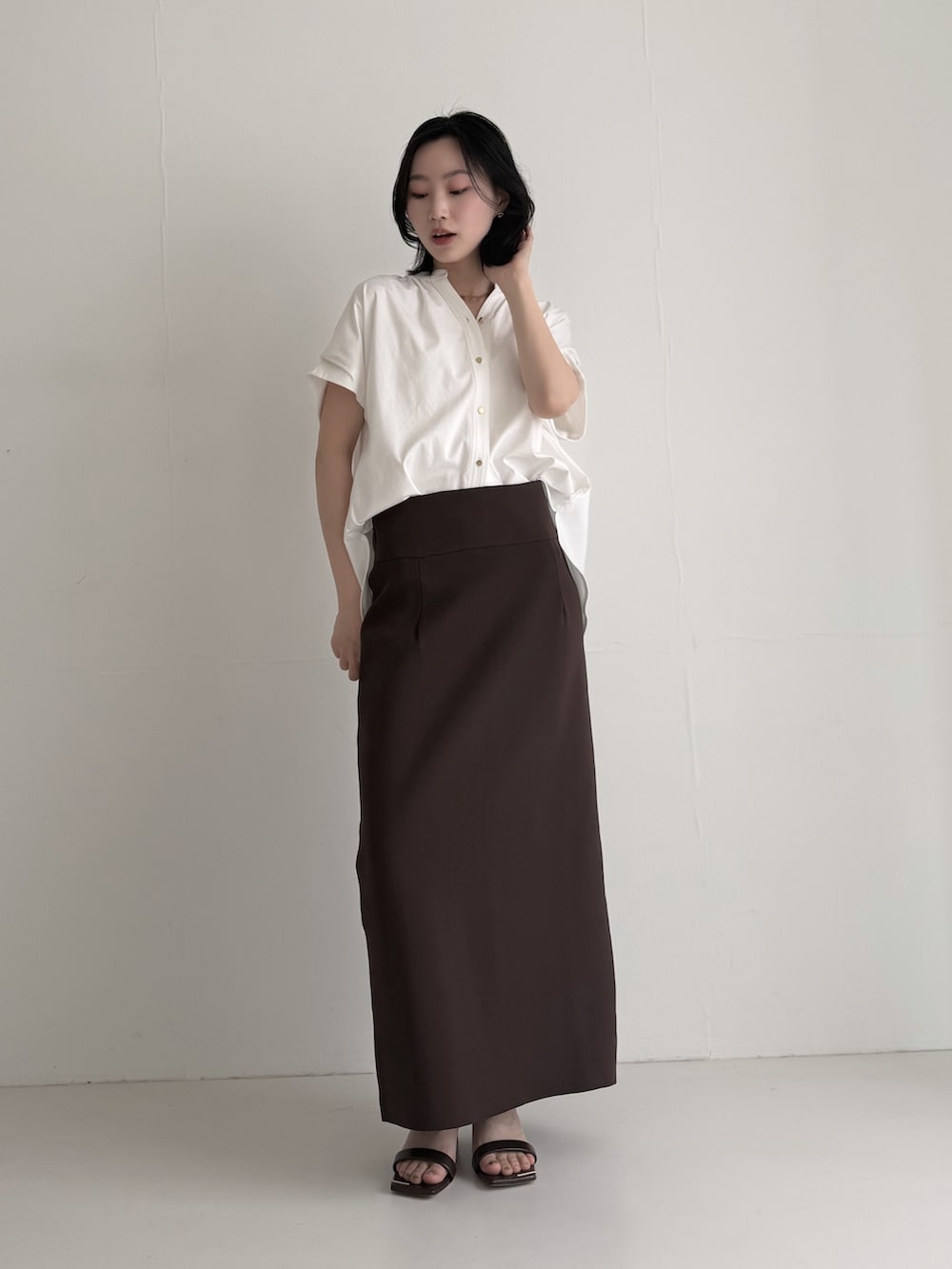 ブラウン系のスカート、ホワイト系のシャツ/ブラウス、ブラウン系のサンダルを着用したレディースの夏コーディネートの2枚目の写真