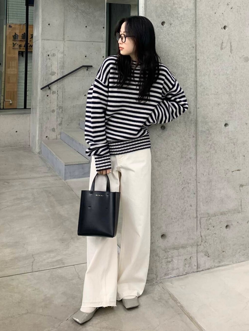 ホワイト系のデニムパンツ、ブラック系のハンドバッグ、グレー系のパンプスを着用したレディースの冬コーディネートの4枚目の写真