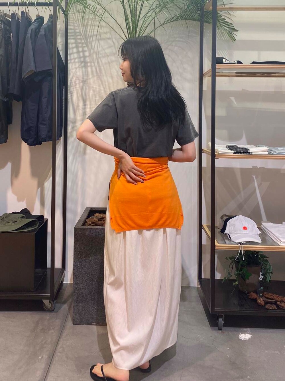 ブラック系のサンダル、オレンジ系のカーディガン/ボレロ、ホワイト系のスカートを着用したレディースの夏コーディネートの5枚目の写真