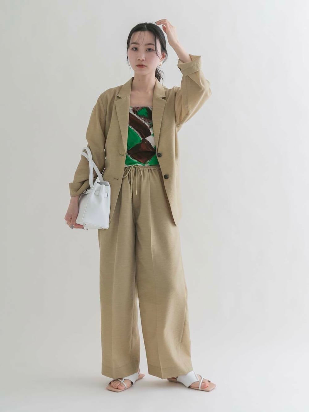 ホワイト系のハンドバッグ、ベージュ系のその他アウター、ベージュ系のその他パンツを着用したレディースの春コーディネートの2枚目の写真