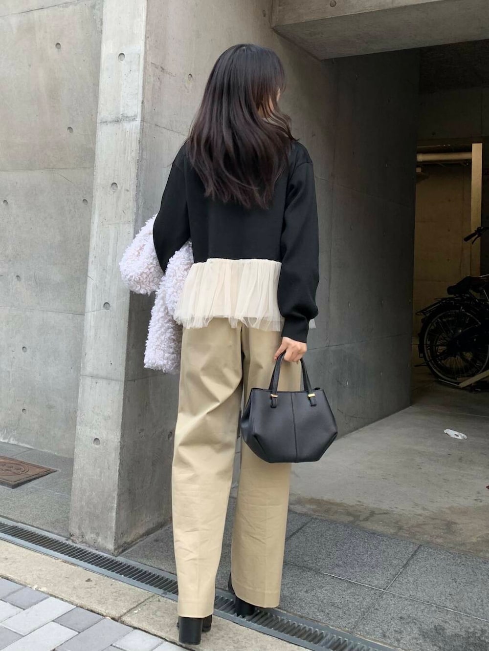 ブラック系のショルダーバッグ、ブラック系のブーツ、ベージュ系のチノパンツを着用したレディースの冬コーディネートの4枚目の写真