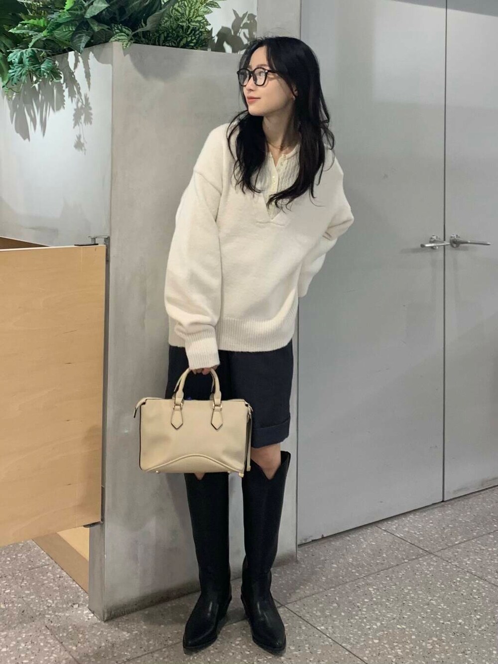 ホワイト系のボストンバッグ、ブラック系のブーツ、グレー系のその他パンツを着用したレディースの冬コーディネートの3枚目の写真