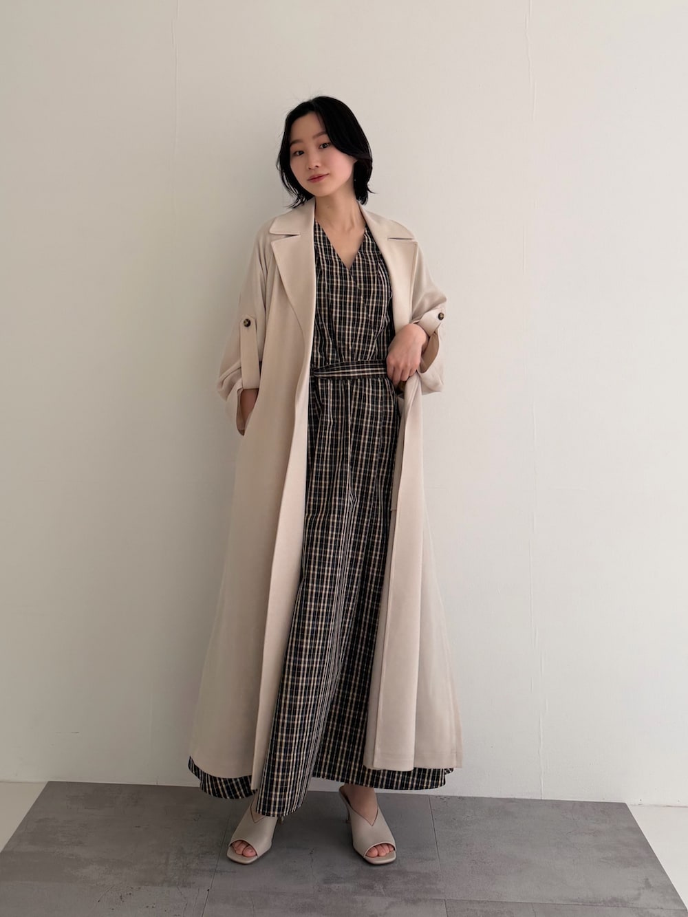 ブラウン系のワンピース、ベージュ系のトレンチコートを着用したレディースの春コーディネートの2枚目の写真