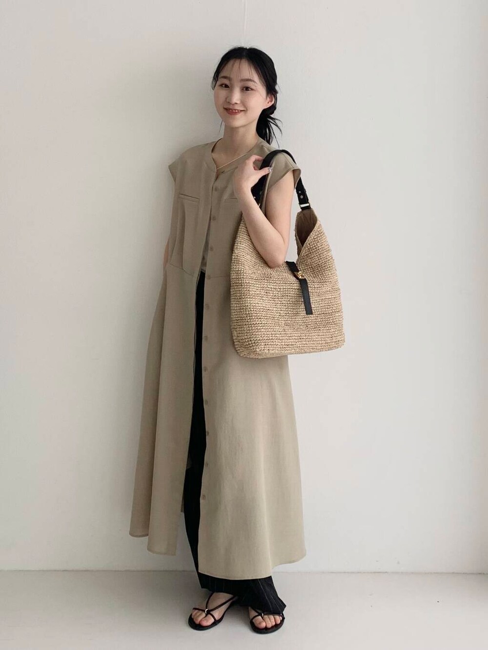 ベージュ系のかごバッグ、ベージュ系のワンピース、ブラック系のその他パンツを着用したレディースの春コーディネートの2枚目の写真