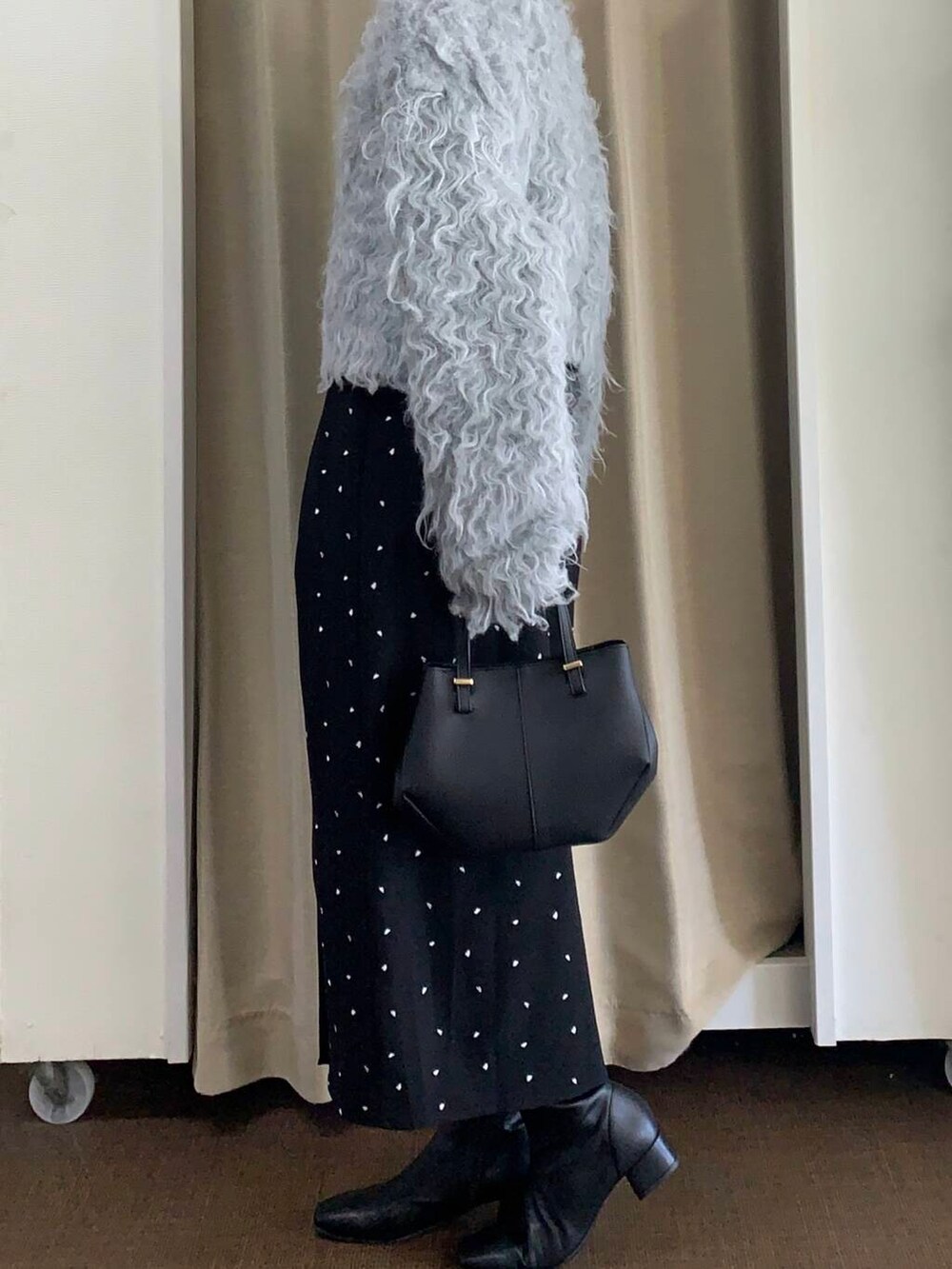 ブラック系のブーツ、ブラック系のショルダーバッグ、ブラック系のスカートを着用したレディースの秋コーディネートの3枚目の写真