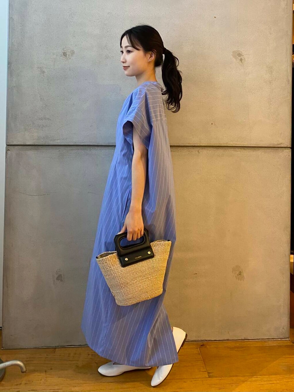 ベージュ系のハンドバッグ、ホワイト系のパンプス、ブルー系のワンピースを着用したレディースの夏コーディネートの4枚目の写真