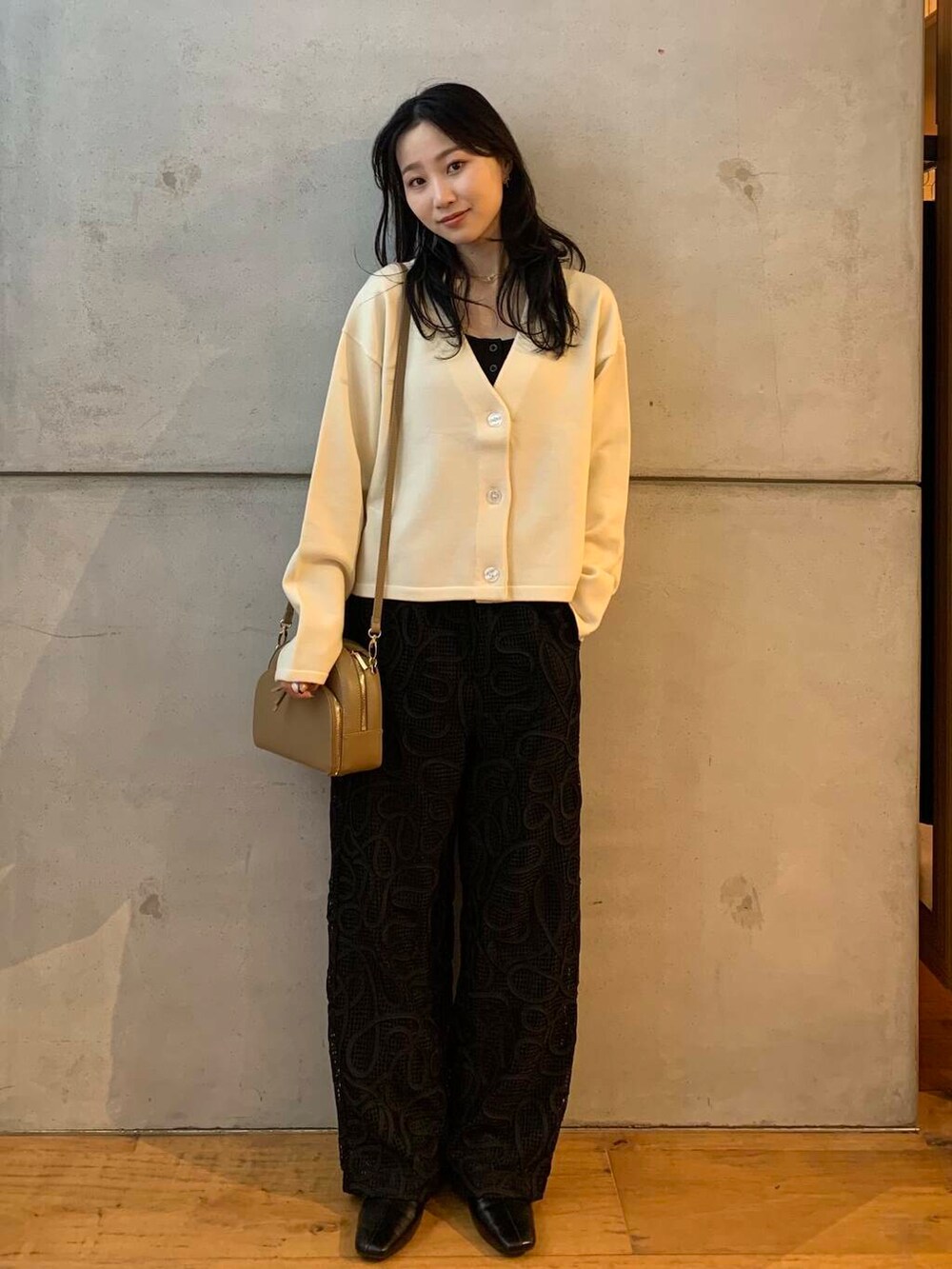 ベージュ系のショルダーバッグ、ホワイト系のカーディガン/ボレロ、ブラック系のブーツを着用したレディースの秋コーディネートの3枚目の写真