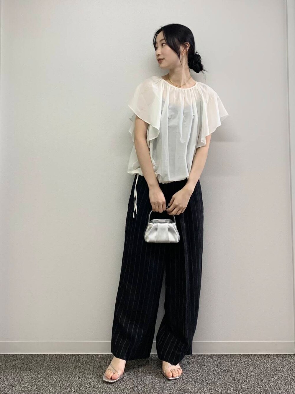 シルバー系のハンドバッグ、ブラック系のその他パンツ、ホワイト系のシャツ/ブラウスを着用したレディースの春コーディネートの2枚目の写真