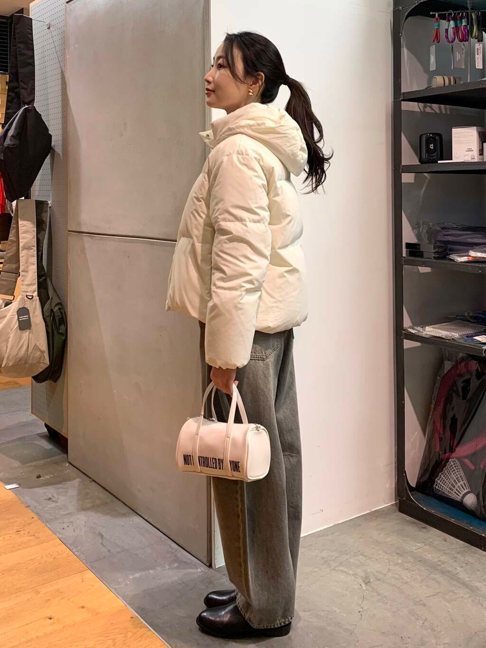 ブラック系のブーツ、ホワイト系のボストンバッグ、グリーン系のデニムパンツを着用したレディースの冬コーディネートの4枚目の写真