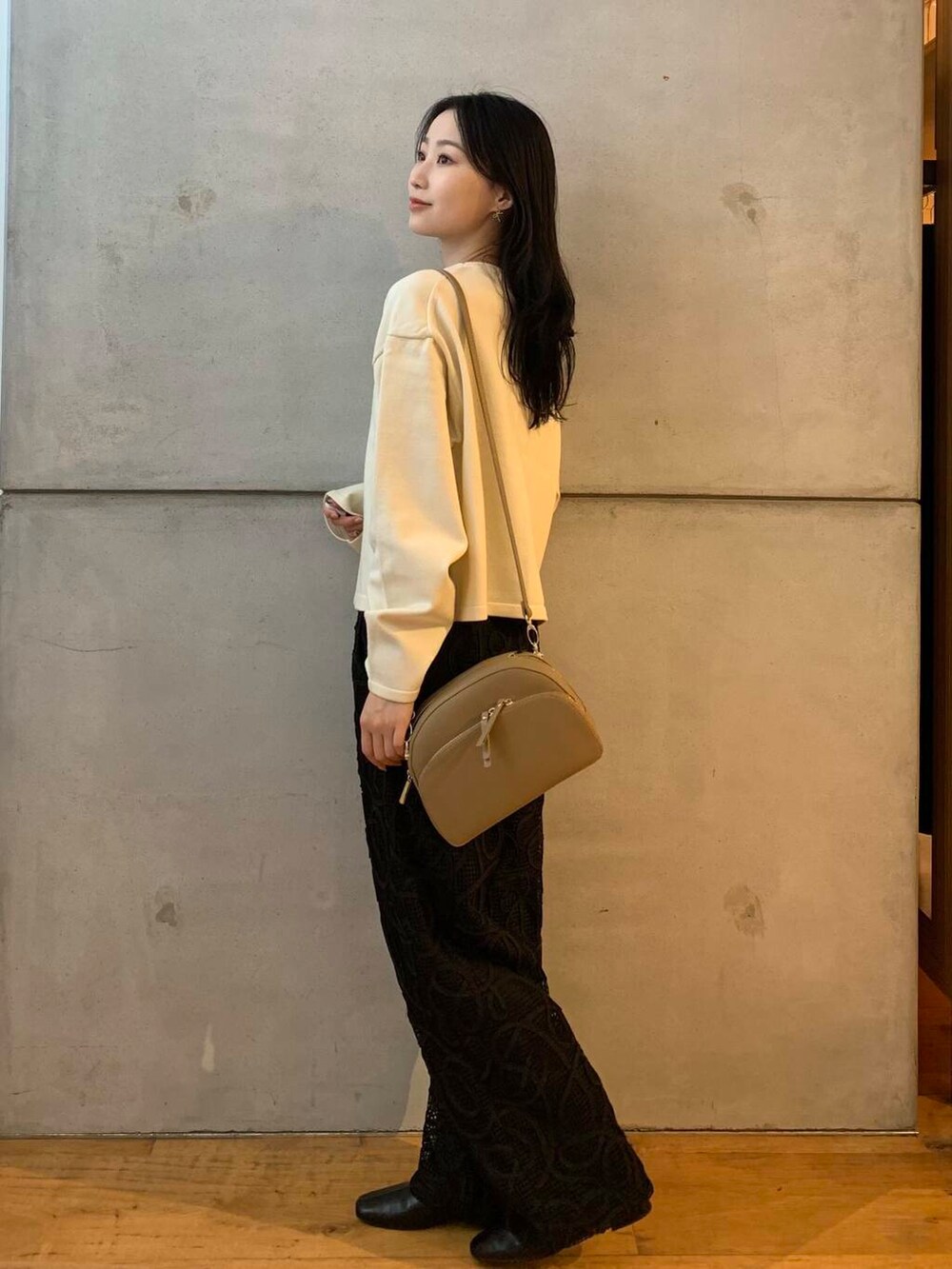 ベージュ系のショルダーバッグ、ホワイト系のカーディガン/ボレロ、ブラック系のブーツを着用したレディースの秋コーディネートの5枚目の写真