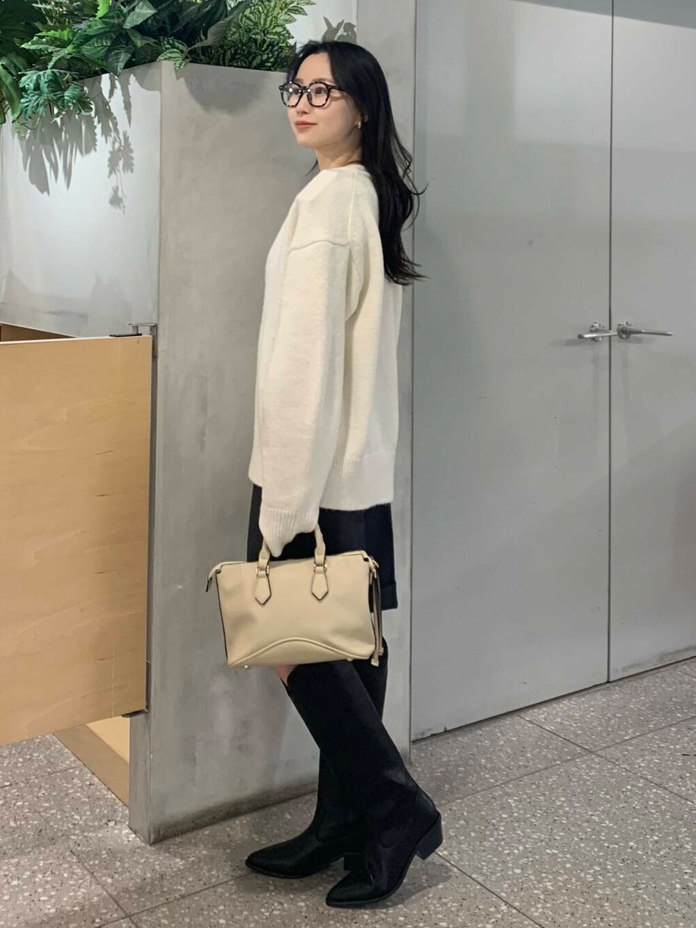 ホワイト系のボストンバッグ、ブラック系のブーツ、グレー系のその他パンツを着用したレディースの冬コーディネートの5枚目の写真