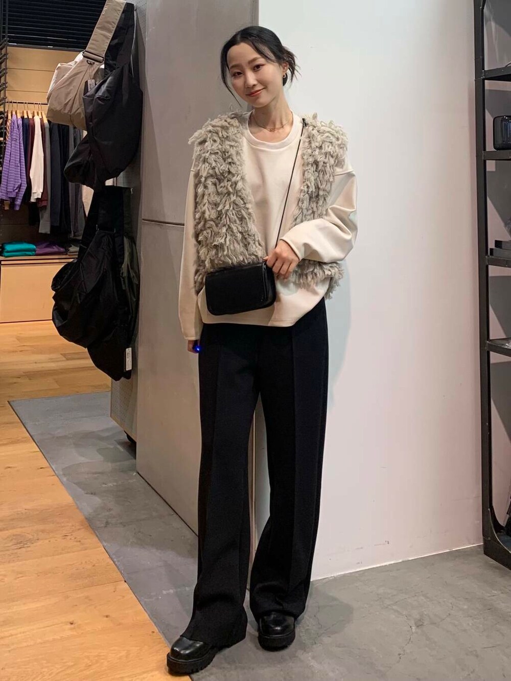 ブラック系のブーツ、グレー系のスウェット、グレー系のベストを着用したレディースの冬コーディネートの2枚目の写真