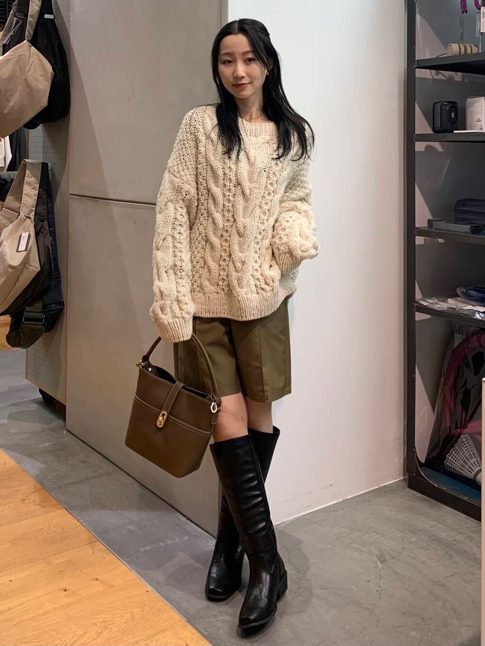 ホワイト系のニット/セーター、ベージュ系のハンドバッグ、ブラック系のブーツを着用したレディースの冬コーディネートの2枚目の写真
