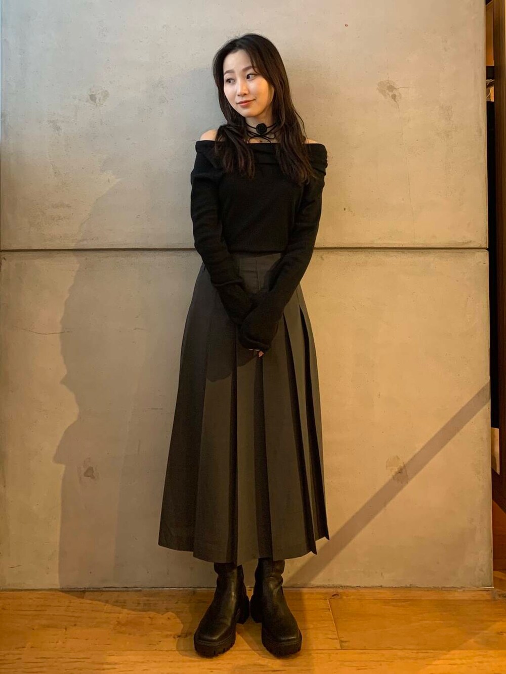 グレー系のスカート、ブラック系のブーツ、ブラック系のTシャツ/カットソーを着用したレディースの秋コーディネートの7枚目の写真