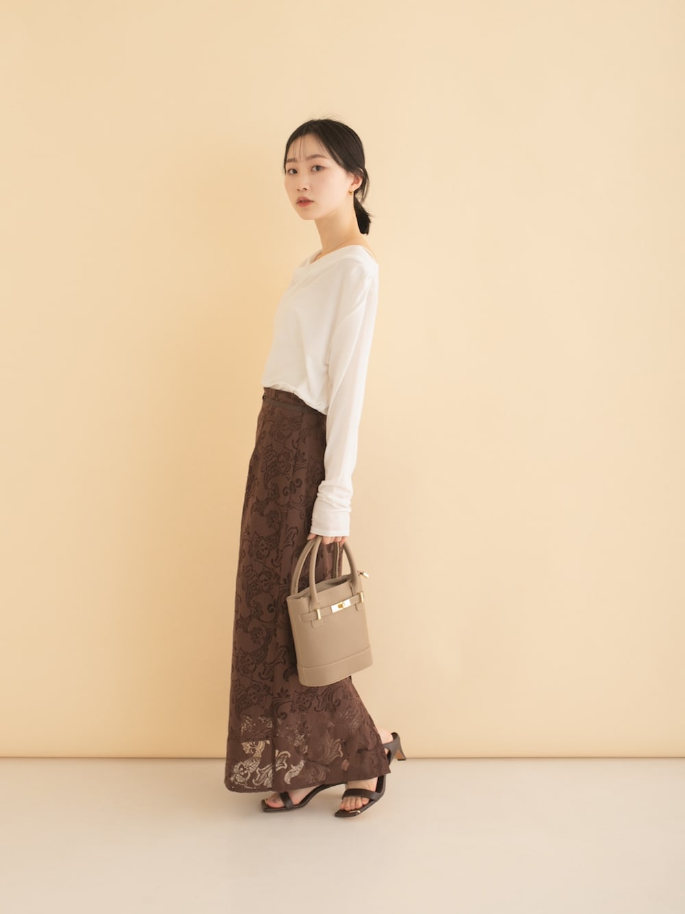 ブラウン系のスカート、ホワイト系のTシャツ/カットソーを着用したレディースの春コーディネートの2枚目の写真