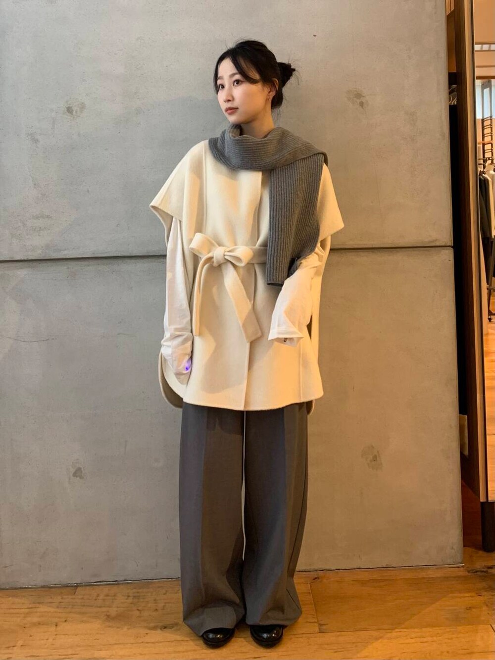 グレー系のその他パンツ、ホワイト系のポンチョ、ブラック系のレインシューズを着用したレディースの秋コーディネートの4枚目の写真