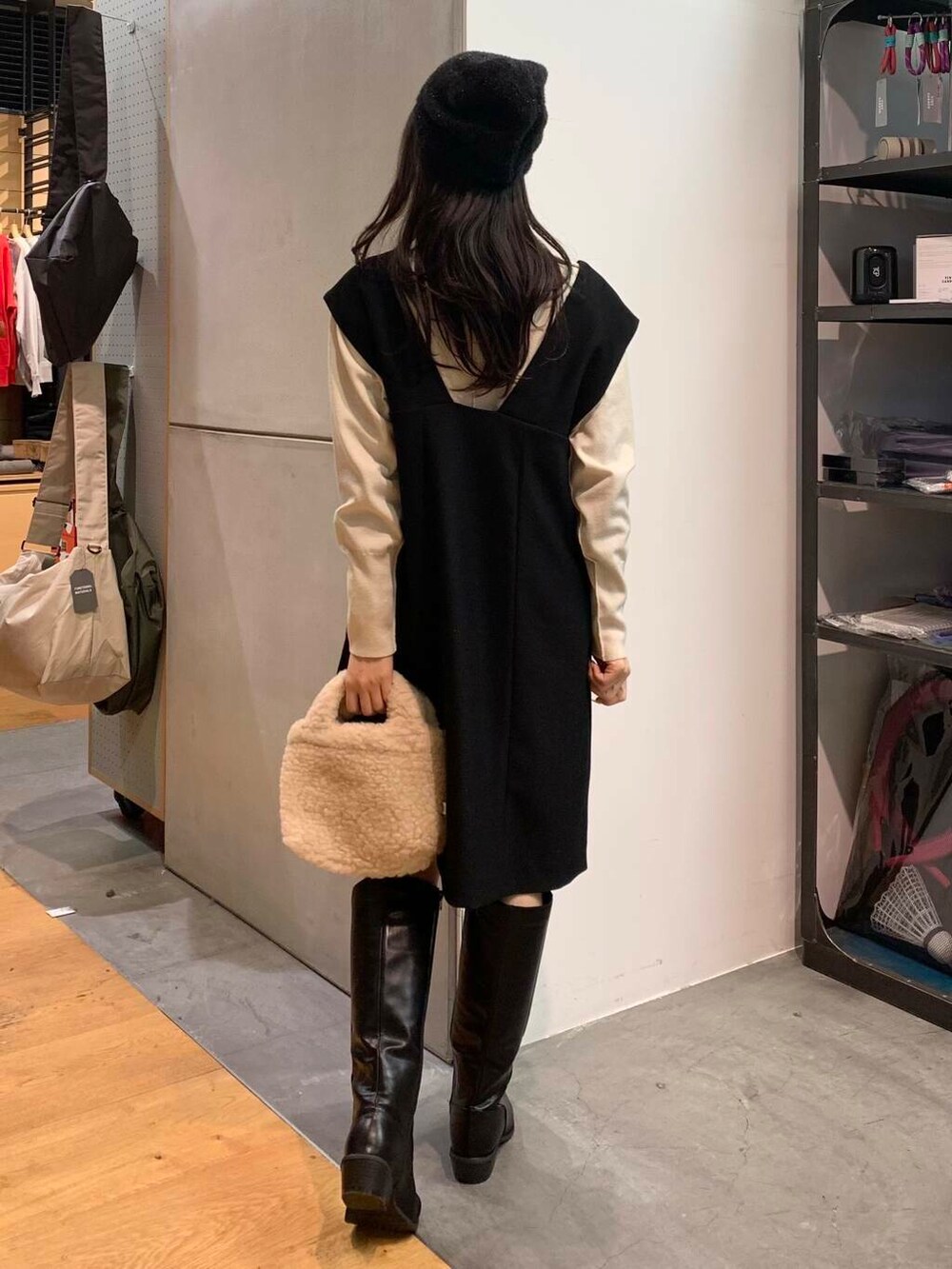 ブラック系のブーツ、ベージュ系のハンドバッグ、ブラック系のワンピースを着用したレディースの冬コーディネートの7枚目の写真