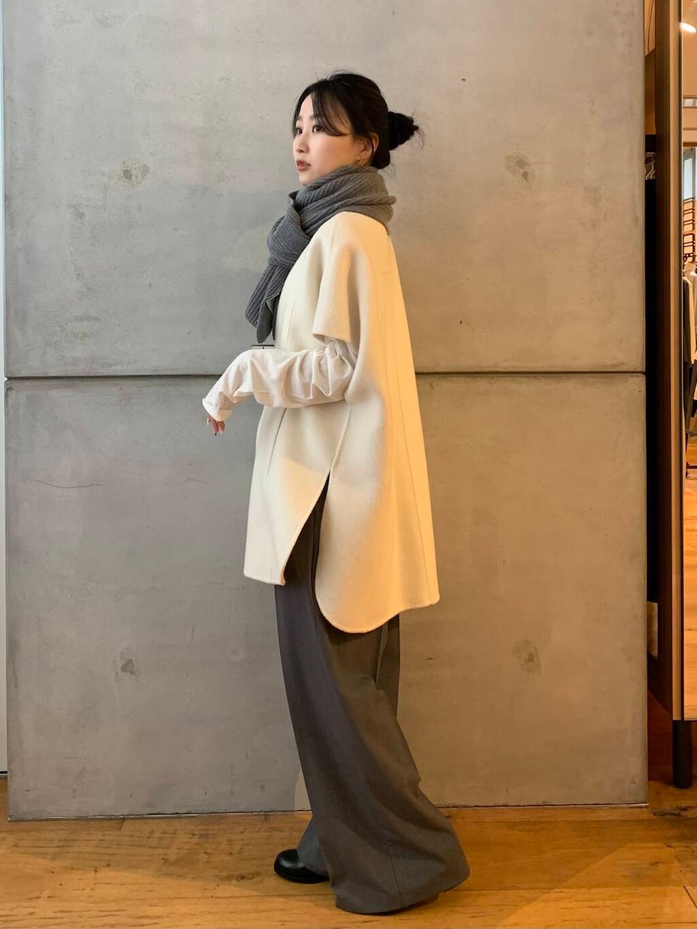 グレー系のその他パンツ、ホワイト系のポンチョ、ブラック系のレインシューズを着用したレディースの秋コーディネートの3枚目の写真