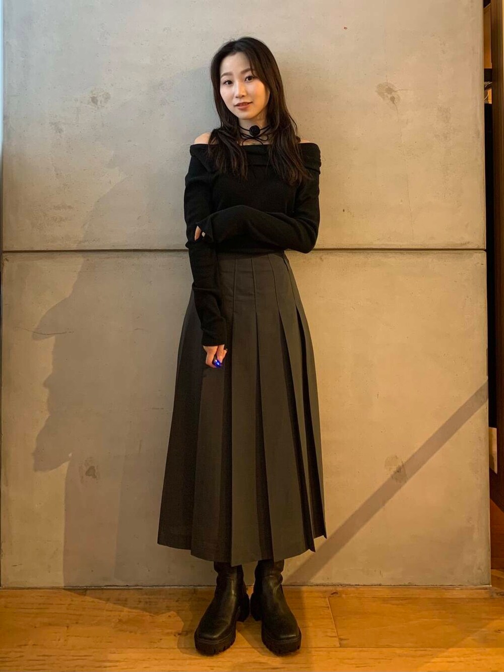 グレー系のスカート、ブラック系のブーツ、ブラック系のTシャツ/カットソーを着用したレディースの秋コーディネートの6枚目の写真