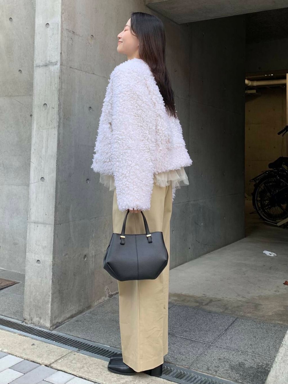 ブラック系のショルダーバッグ、ブラック系のブーツ、ベージュ系のチノパンツを着用したレディースの冬コーディネートの6枚目の写真