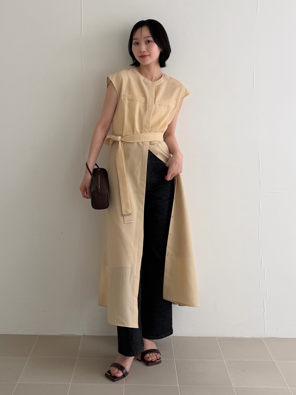 イエロー系のワンピース、ブラック系のデニムパンツ、ブラウン系のサンダルを着用したレディースの夏コーディネートの2枚目の写真