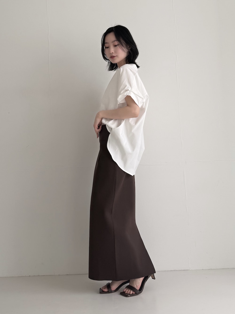 ブラウン系のスカート、ホワイト系のシャツ/ブラウス、ブラウン系のサンダルを着用したレディースの夏コーディネートの3枚目の写真