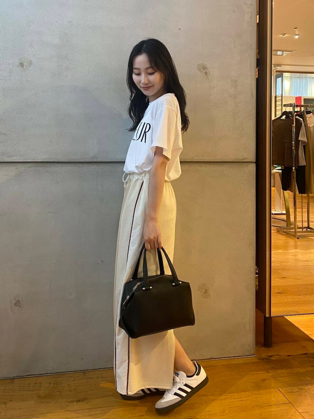 ブラック系のハンドバッグ、ホワイト系のTシャツ/カットソー、ホワイト系のスカートを着用したレディースの夏コーディネートの5枚目の写真