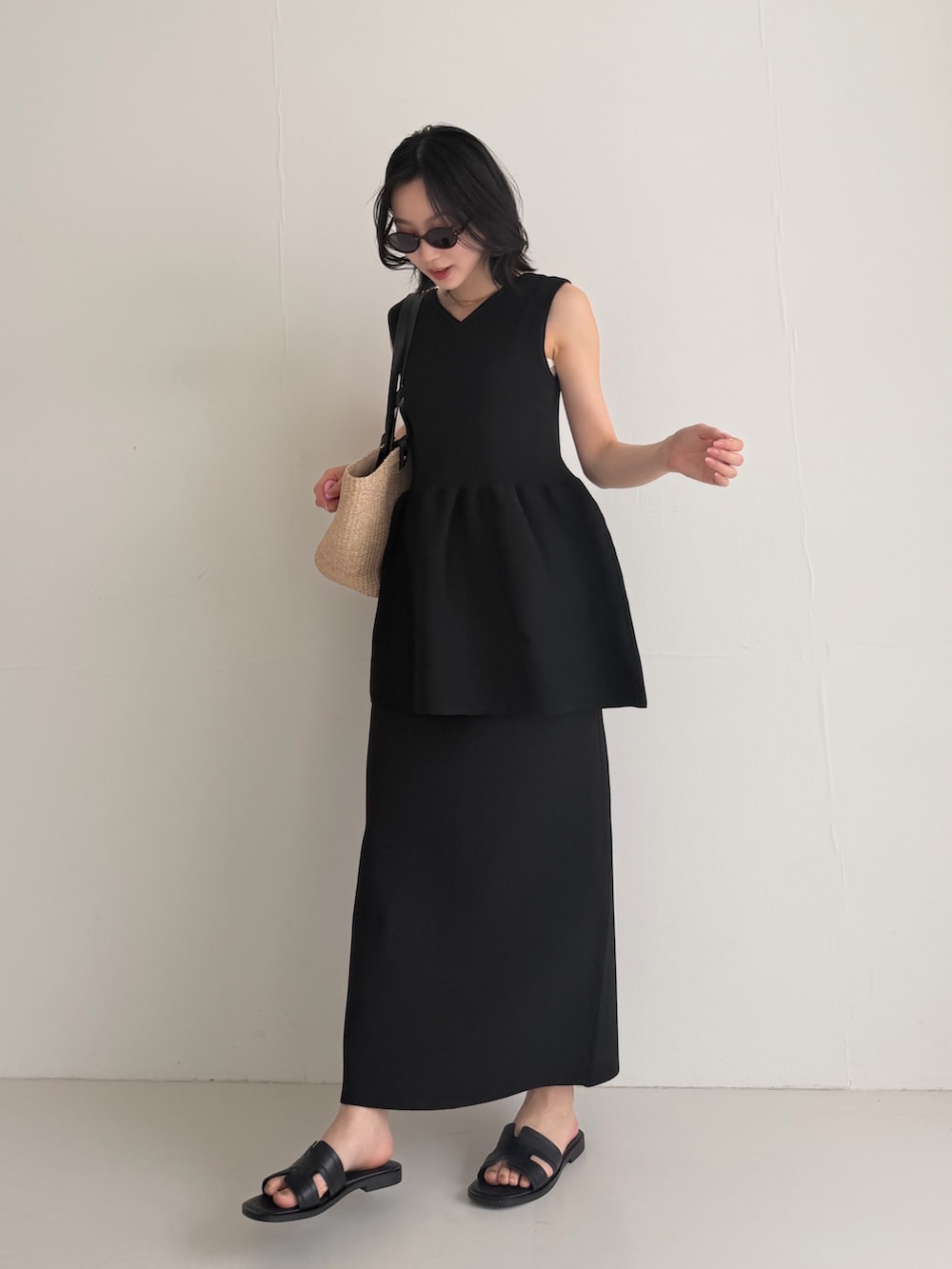 ブラック系のニット/セーター、ブラック系のスカート、ブラック系のサンダルを着用したレディースの夏コーディネートの2枚目の写真