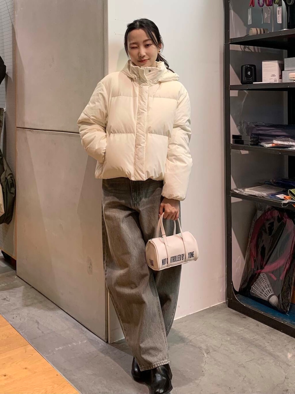 ブラック系のブーツ、ホワイト系のボストンバッグ、グリーン系のデニムパンツを着用したレディースの冬コーディネートの2枚目の写真