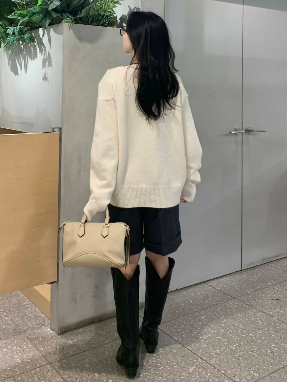 ホワイト系のボストンバッグ、ブラック系のブーツ、グレー系のその他パンツを着用したレディースの冬コーディネートの7枚目の写真