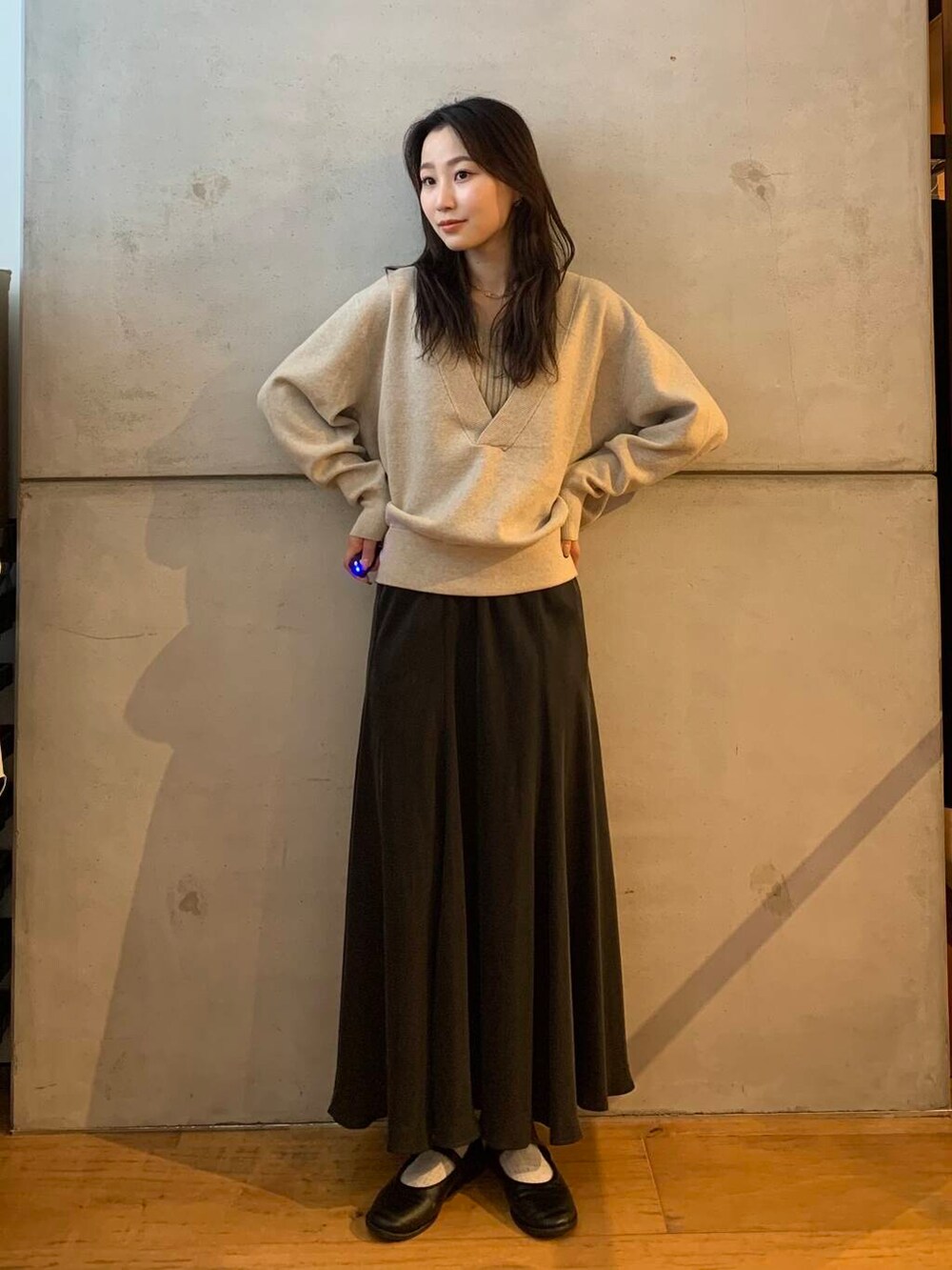 グレー系のスカート、ベージュ系のタンクトップ、ベージュ系のニット/セーターを着用したレディースの秋コーディネートの4枚目の写真